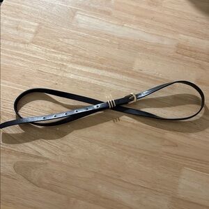 Black faux leather skinny belt with gold hardware and triple loop.